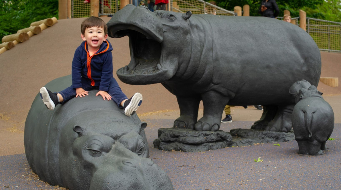 A boy sits atop a hippo sculpture