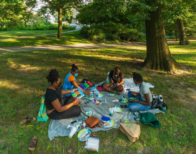Parkgoers painting under cooling shade